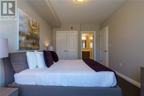 A bedroom with a large bed and a painting on the wall.