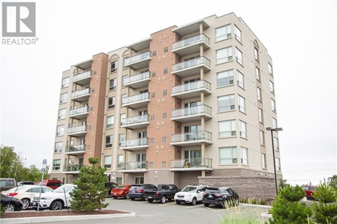 A large apartment building with a parking lot in front.