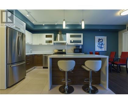 A modern kitchen with a refrigerator, bar stools, and a counter.