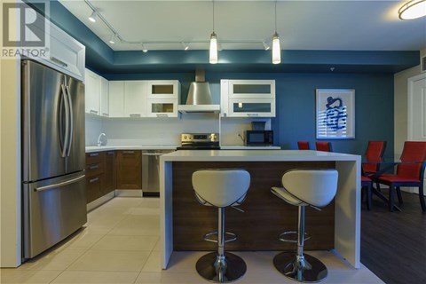 A modern kitchen with a refrigerator, bar stools, and a counter.