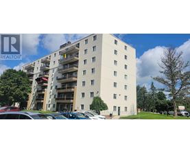 A large white apartment building with a parking lot in front.