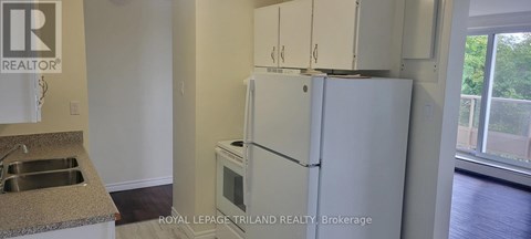A white refrigerator in a kitchen with a sink and a window.