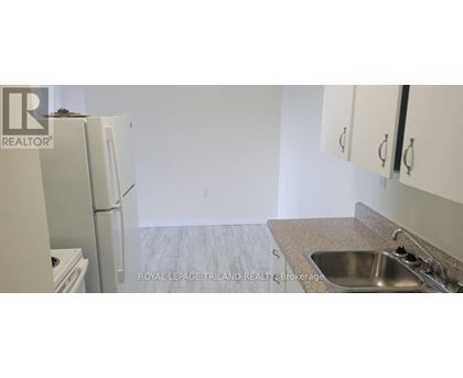 A kitchen with a sink, refrigerator and cabinets.