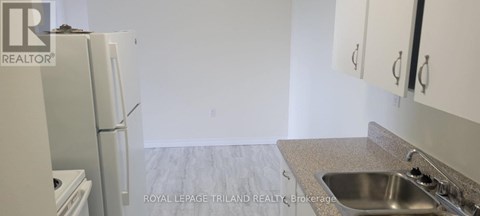 A kitchen with a sink, refrigerator and cabinets.