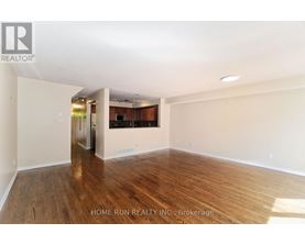 A spacious room with wooden flooring and white walls.
