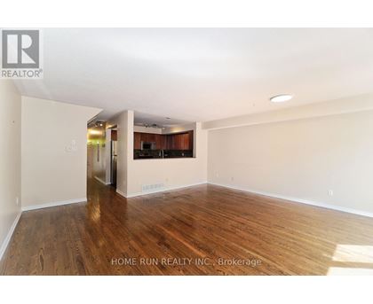 A spacious room with wooden flooring and white walls.
