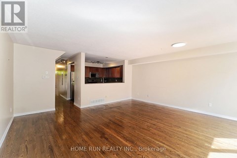 A spacious room with wooden flooring and white walls.