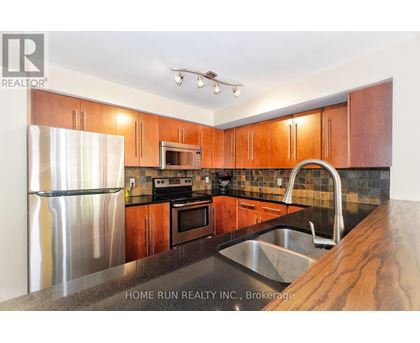 A kitchen with wooden cabinets and a stainless steel refrigerator.