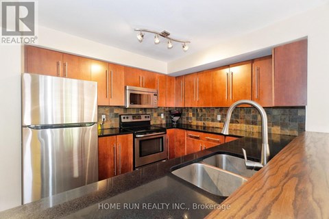 A kitchen with wooden cabinets and a stainless steel refrigerator.