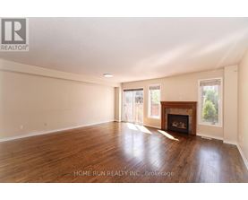A spacious room with a fireplace and wood flooring.