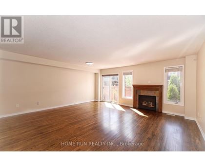 A spacious room with a fireplace and wood flooring.