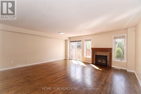A spacious room with a fireplace and wood flooring.