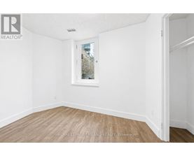 A white room with a window and wooden flooring.