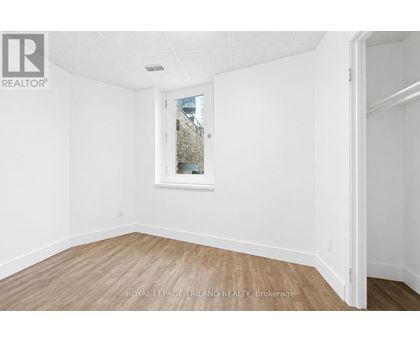 A white room with a window and wooden flooring.