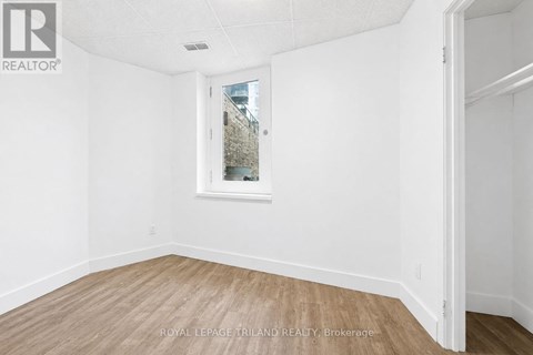 A white room with a window and wooden flooring.