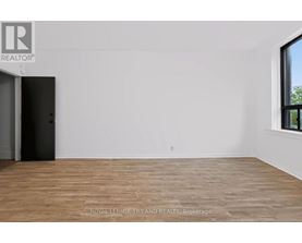 A room with a wooden floor and a door on the left side.