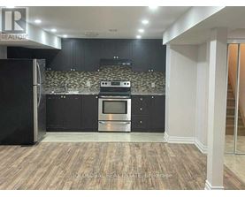 A modern kitchen with dark cabinets and a stainless steel refrigerator.