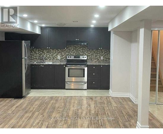 A modern kitchen with dark cabinets and a stainless steel refrigerator.