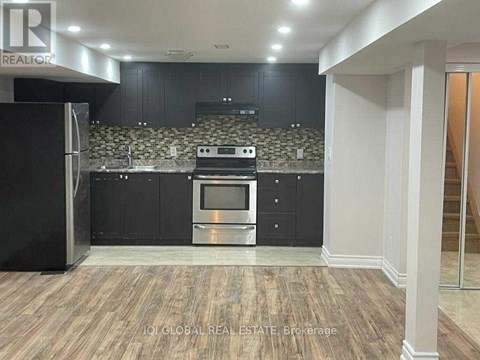 A modern kitchen with dark cabinets and a stainless steel refrigerator.