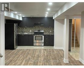 A kitchen with black cabinets and a stone backsplash.