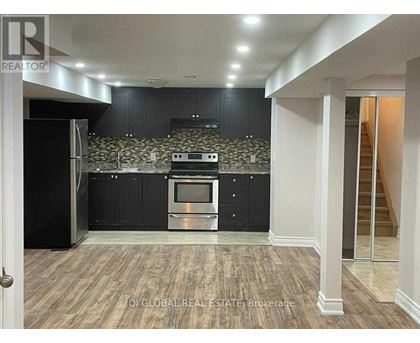 A kitchen with black cabinets and a stone backsplash.