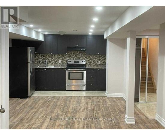 A kitchen with black cabinets and a stone backsplash.
