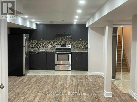 A kitchen with black cabinets and a stone backsplash.