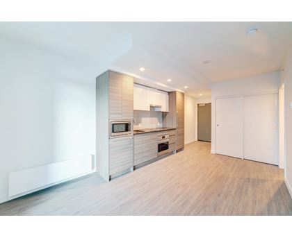 A modern kitchen with wooden floors and white walls.