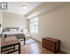A bedroom with a bed, chair, and nightstand.