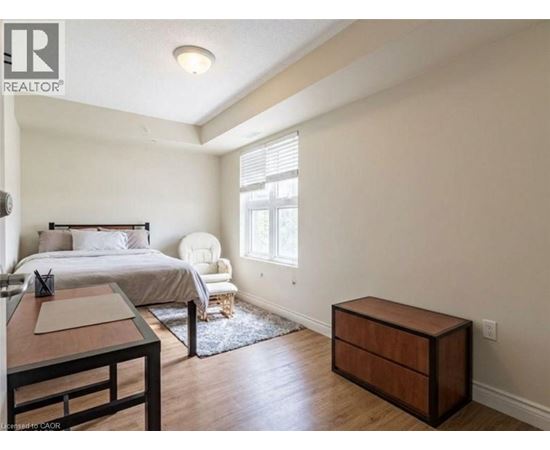 A bedroom with a bed, chair, and nightstand.