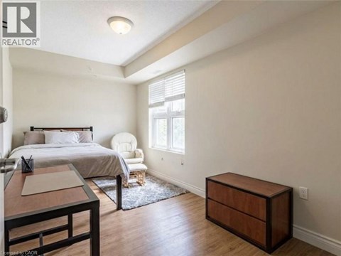 A bedroom with a bed, chair, and nightstand.