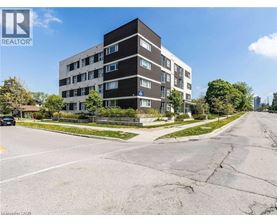 A tall apartment building with a parking lot in front of it.