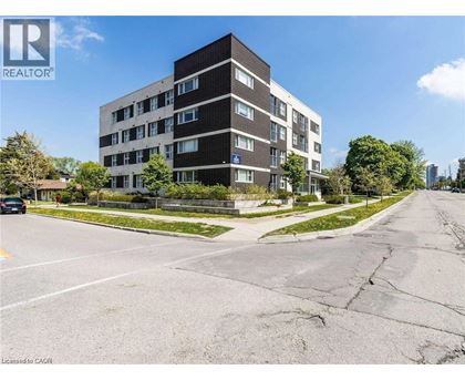 A tall apartment building with a parking lot in front of it.