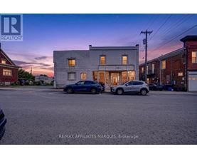A blue car is parked in front of a building with a sign that reads RE/MAX Affiliates Marquis, Brokerage.