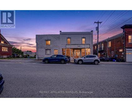 A blue car is parked in front of a building with a sign that reads RE/MAX Affiliates Marquis, Brokerage.