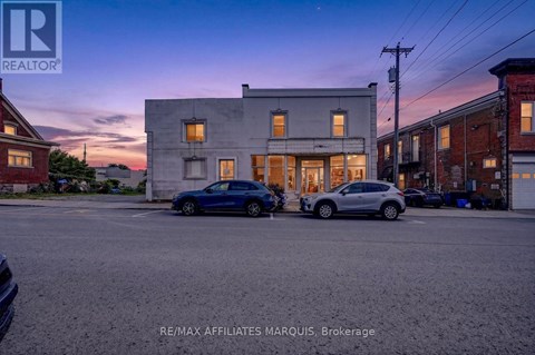 A blue car is parked in front of a building with a sign that reads RE/MAX Affiliates Marquis, Brokerage.