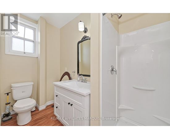 A white bathroom with a toilet, sink, and mirror.