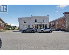 Two cars are parked in front of a white building.