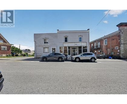 Two cars are parked in front of a white building.