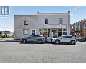 Two cars are parked in front of a building with a sign that reads "REMAX AFFILIATES MARQUIS Brokerage.".