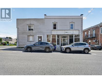 Two cars are parked in front of a building with a sign that reads "REMAX AFFILIATES MARQUIS Brokerage.".