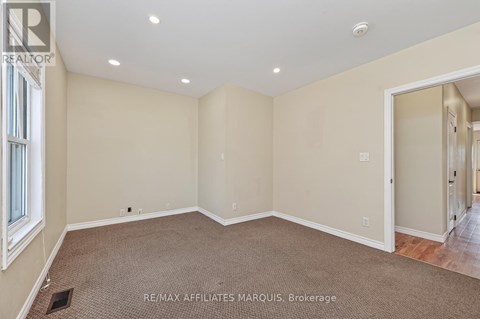 A spacious room with beige walls and carpeted floor.
