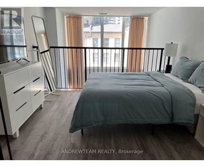 A bedroom with a bed, nightstand, and chair.