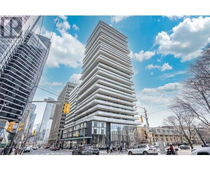A tall, modern building with a curved facade stands in the middle of a bustling city street.
