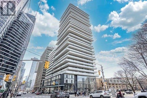 A tall, modern building with a curved facade stands in the middle of a bustling city street.
