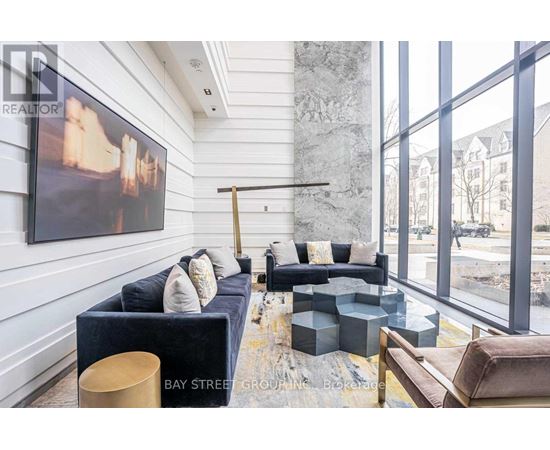 A living room with a large painting on the wall and a view of the street outside the window.