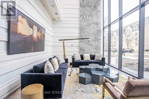 A living room with a large painting on the wall and a view of the street outside the window.