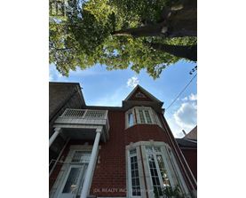 A red brick building with white trim and a large tree in the foreground.