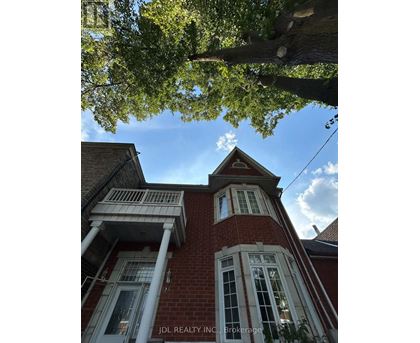 A red brick building with white trim and a large tree in the foreground.
