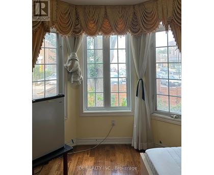 A window with a curtain and a window cleaner on the sill.